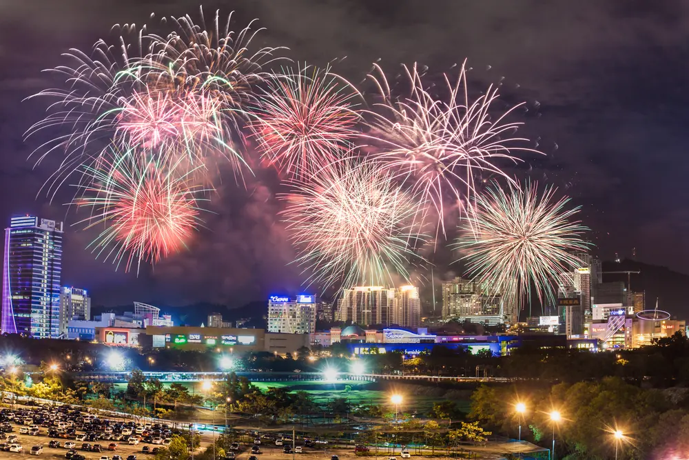 Fireworks burst over a city skyline at night.